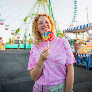 Red haired lady with a lollipop at an amusement park